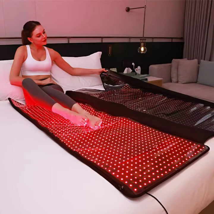 Woman using a red light therapy mat in a bedroom setting