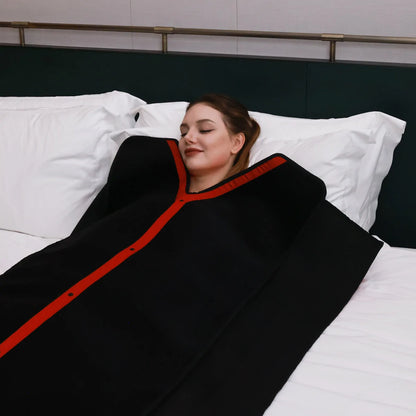 Woman lying on a bed wearing a black and red led therapy blanket.