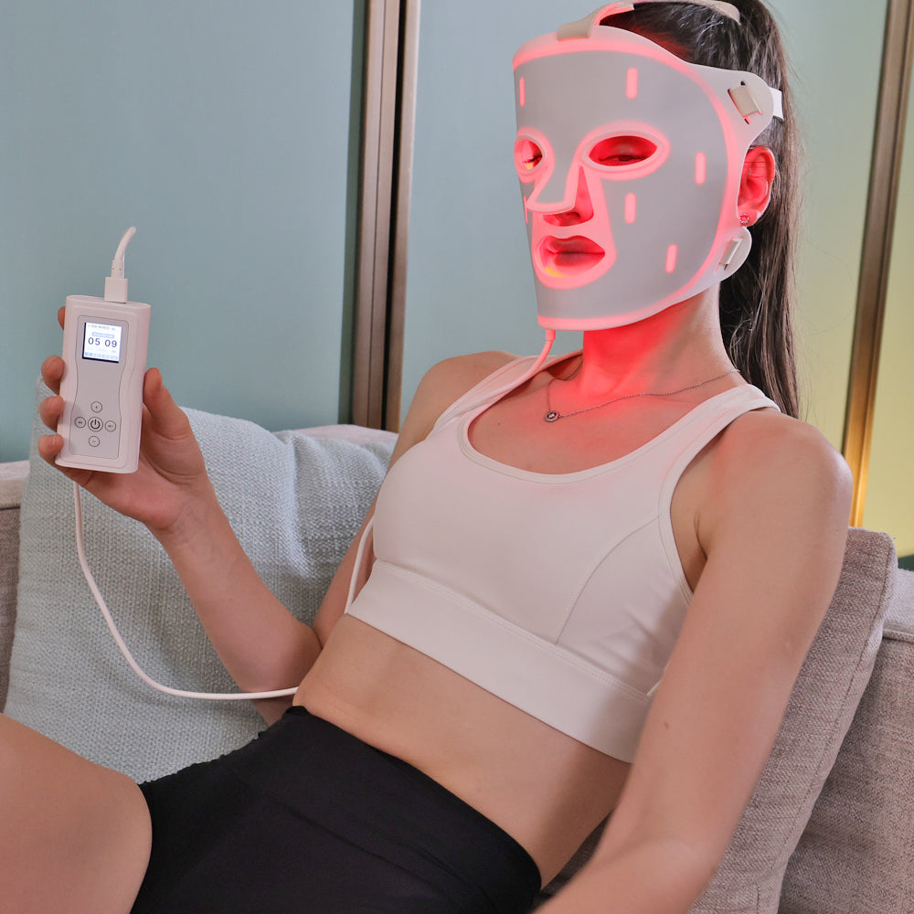 Woman wearing a red light therapy mask, relaxing during a skincare session.